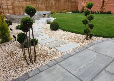 A gravel path and stepping stones in a contemporary garden with topiary