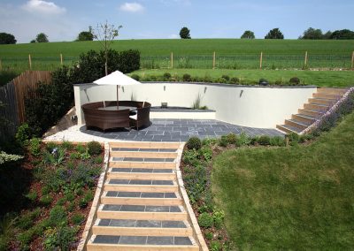 Contemporary patio with curved wall and steps in a rural garden
